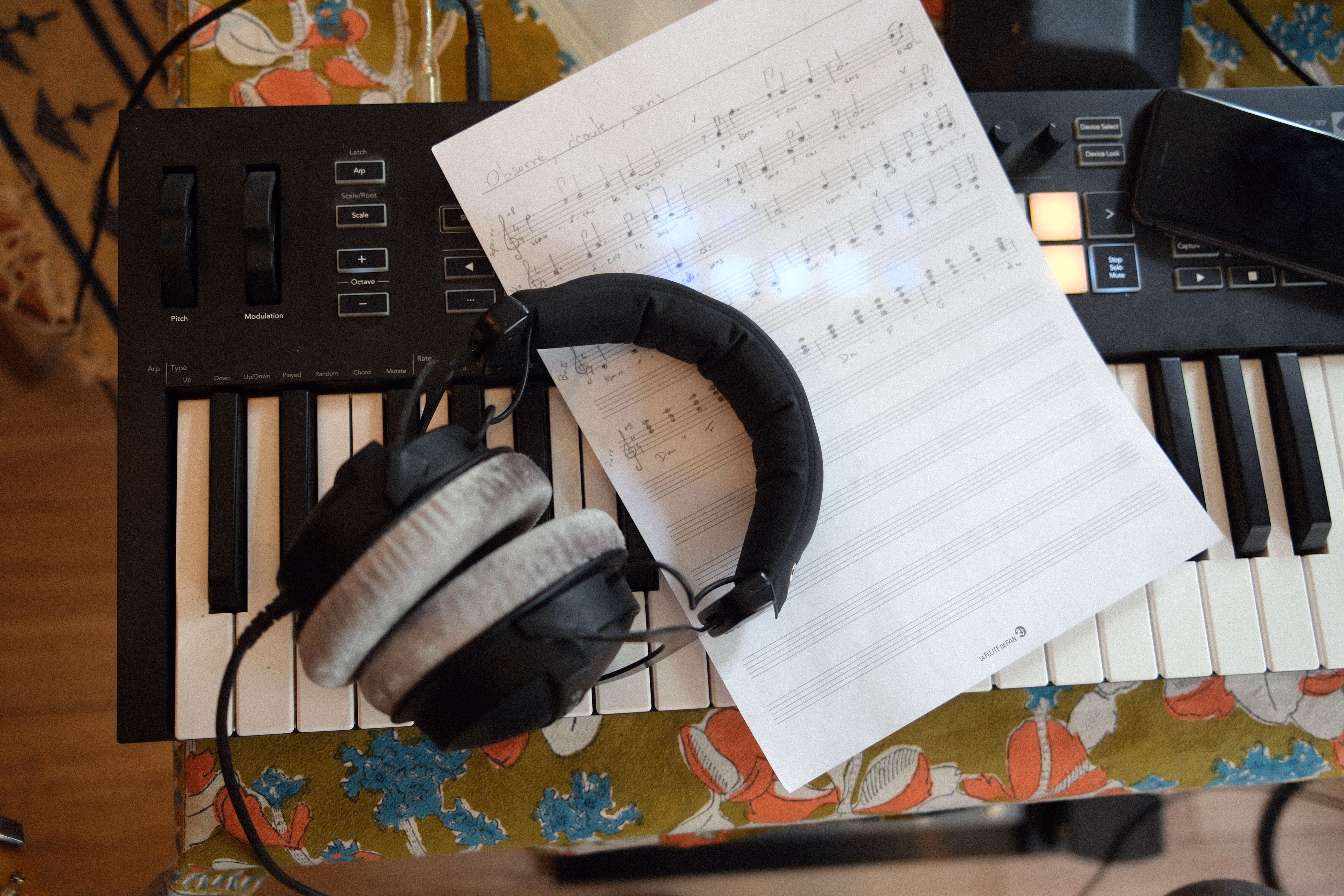 Un casque audio et une partition manuscrite posés sur les touches d'un clavier MIDI